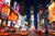 Times Square bei Nacht mit leuchtenden Werbetafeln und vorbeifahrenden gelben Taxis.