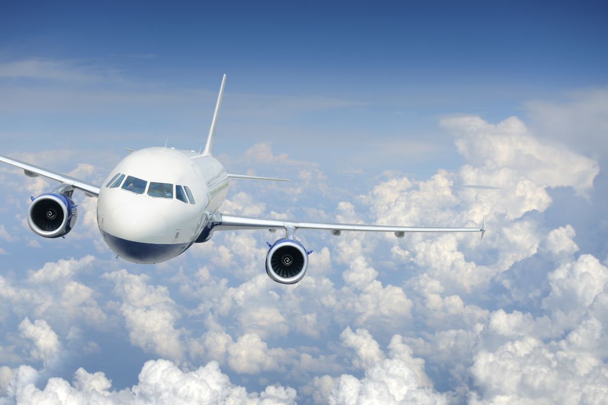 Ein Flugzeug fliegt in einem blauen, mit Wolken bedeckten Himmel.