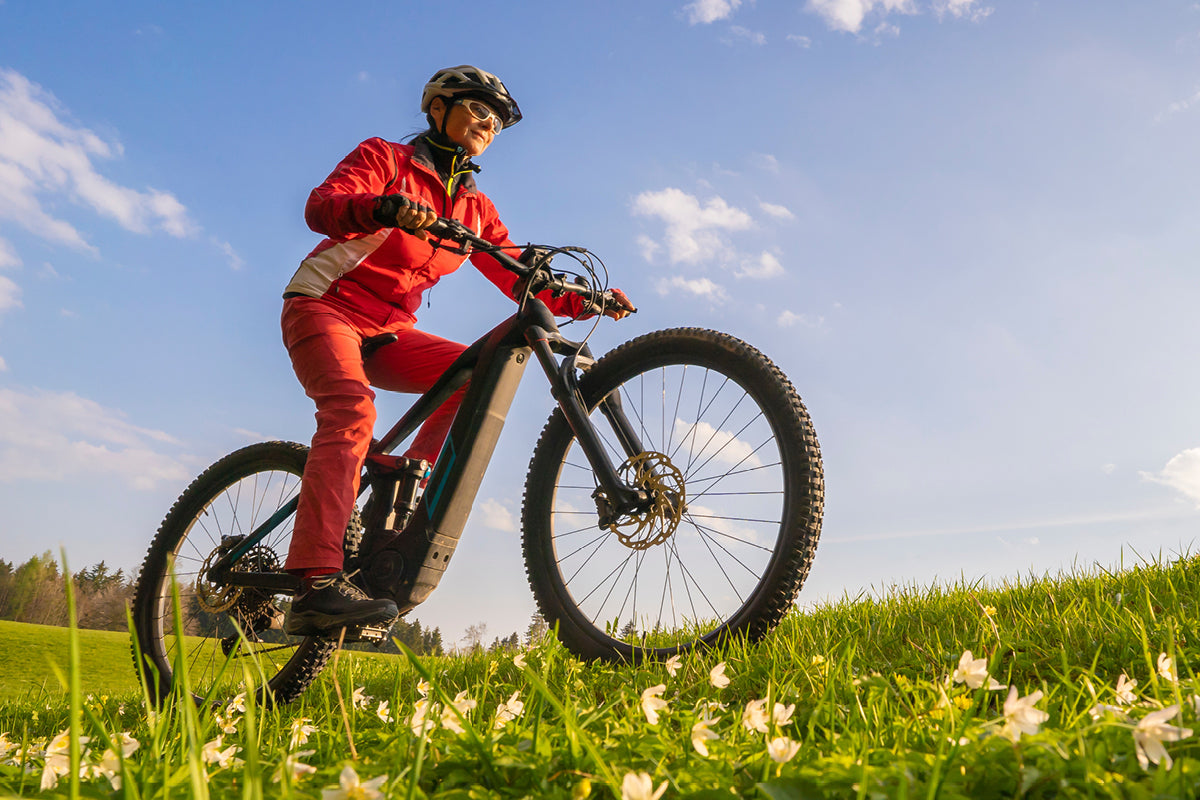 Eine Frau sitzt in passender Uniform auf einem fahrrad und fährt durchs Grüne.