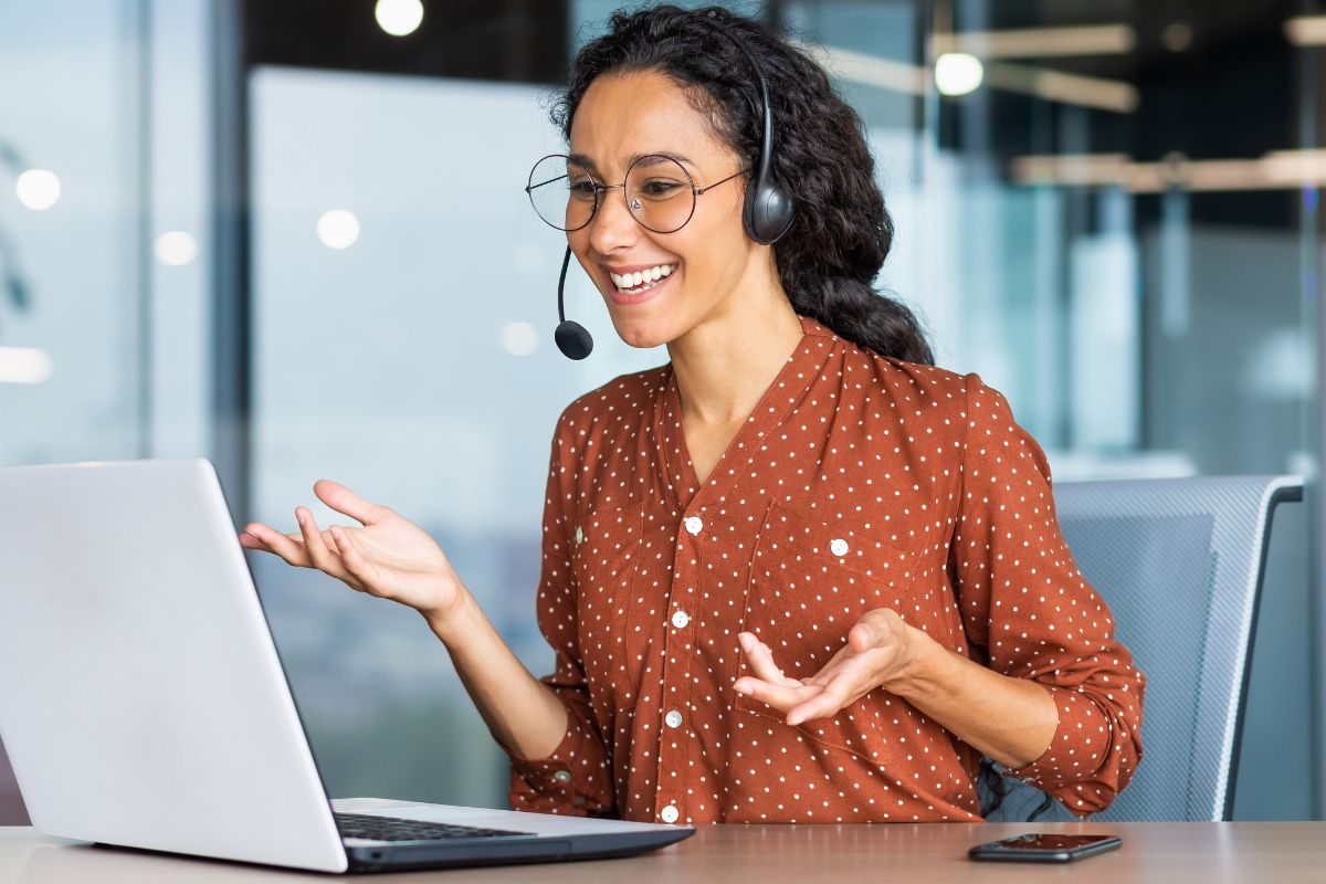 Eine Telefonistin telefoniert mit einem Kunden und lächelt.