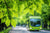 Grüne Blätter im Vordergrund, im Hintergrund ein grüner Bus, Symbol für umweltfreundliche Mobilität