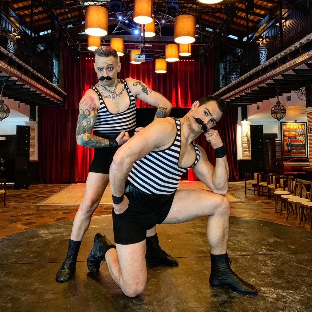 Zwei Artisten in gestreiften Outfits in einer Theaterkulisse.