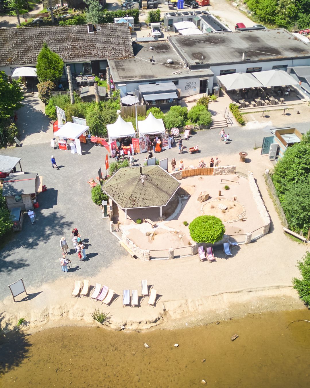 Luftaufnahme des Tierparks Rheinböllen am Seeufer. Im Hintergrund befinden sich die Ausstellerstände der Jobmesse „Jobs im Park“ auf dem Veranstaltungsgelände.