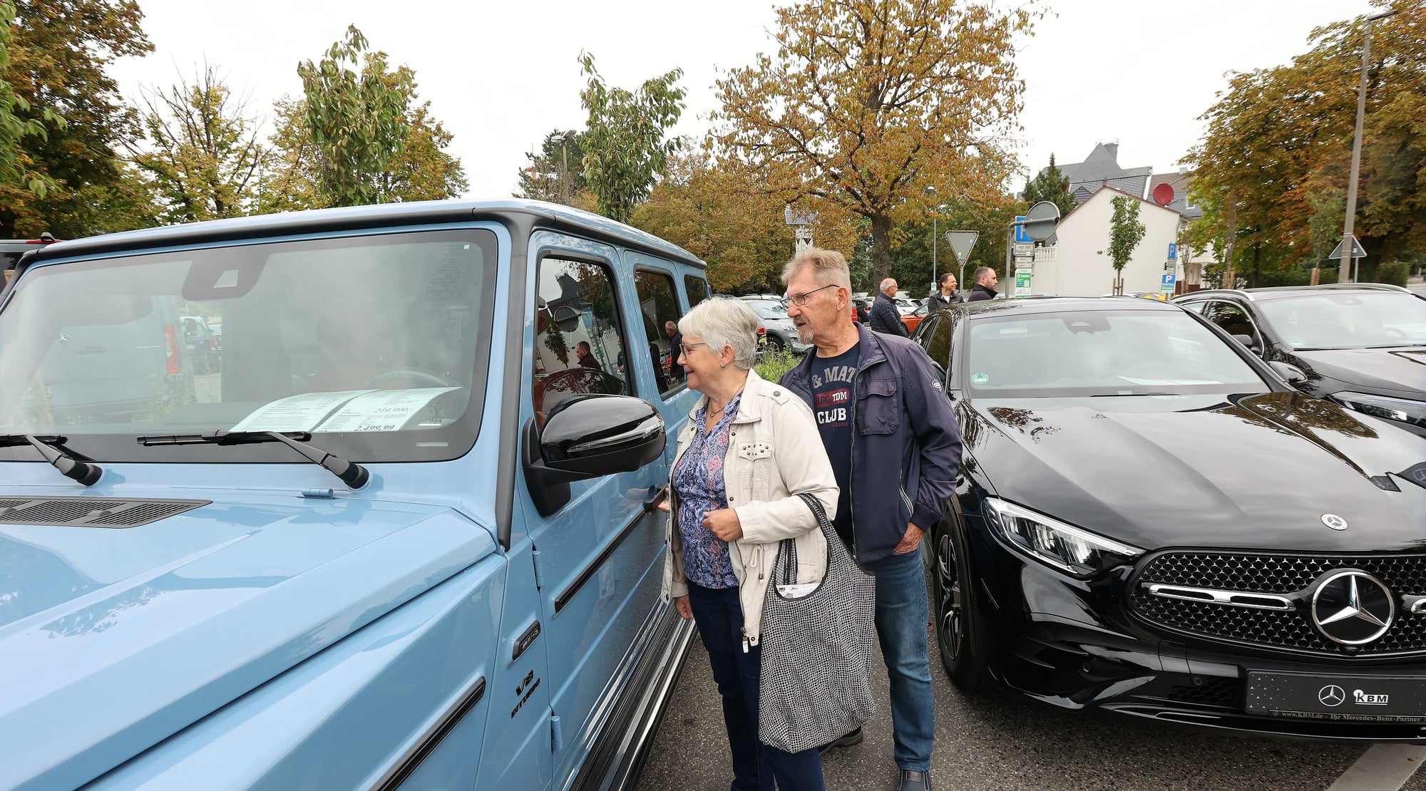 Besucher der Autoausstellung Neuwied unterhalten sich in einer kleinen Gruppe neben den ausgestellten Autos.