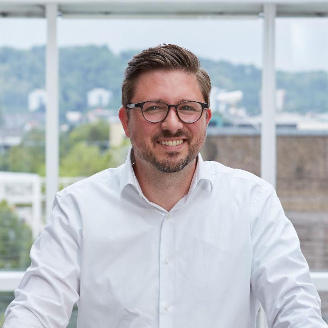 Porträtfoto von Christopher Dold von der evm, der Praxisbeispiele für erfolgreiche E-Mobilitätsprojekte mit regionalen Partnern präsentiert.