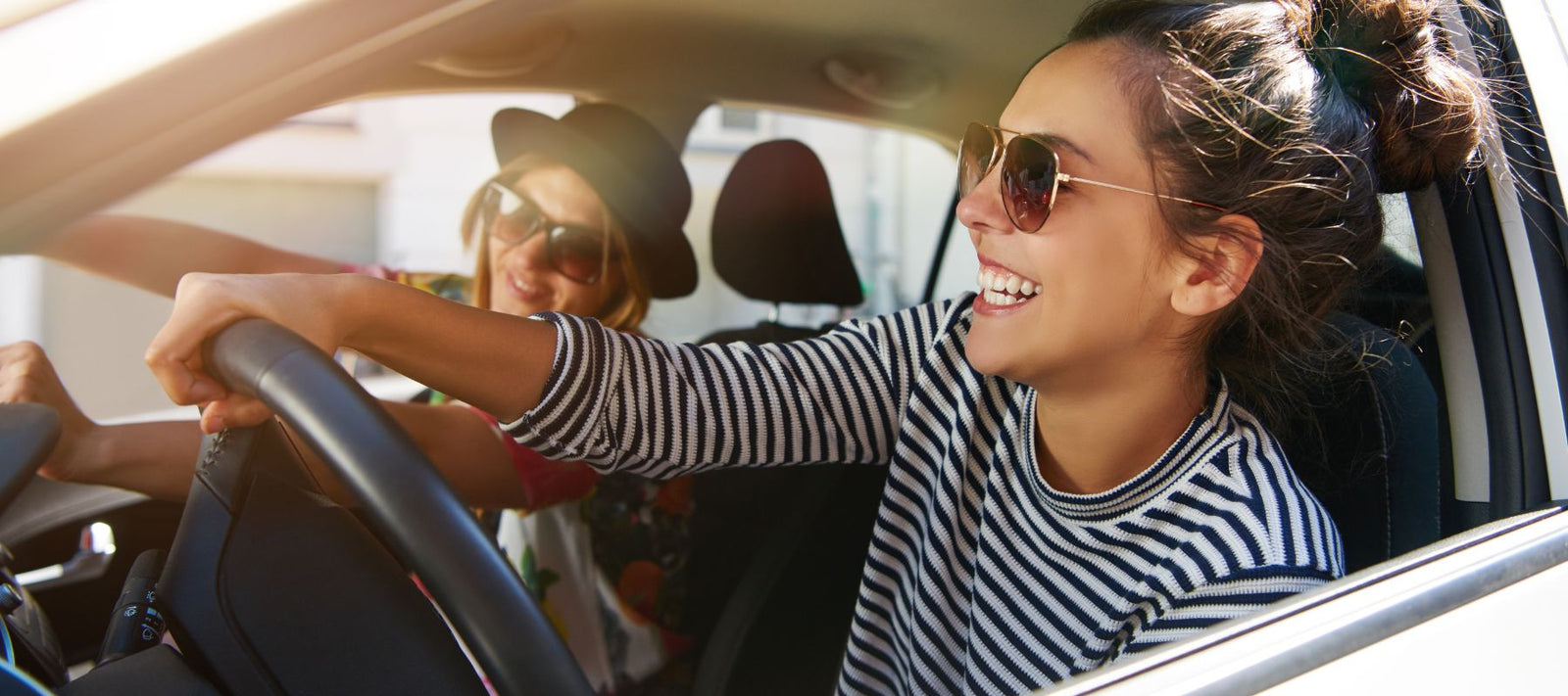 Zwei junge Frauen sind am Autofahren und scheinen Spaß zu haben.