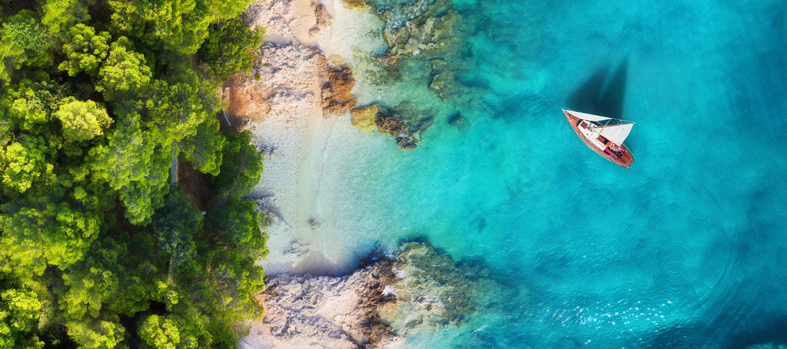 Küste mit einem Schiff im Wasser und Rechts ein Wald 