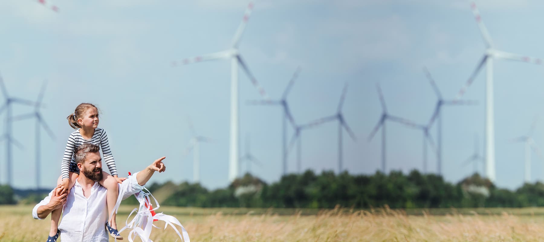 Ein Vater zeigt seiner Tochter die Funktionalität von Windrädern auf einem Feld.