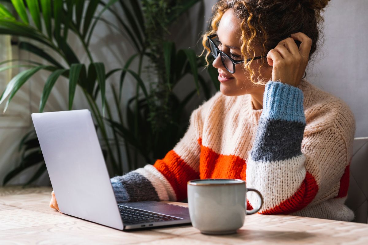 Eine Frau schaut sich freudig eine digitale Veranstaltung auf ihrem Laptop an.